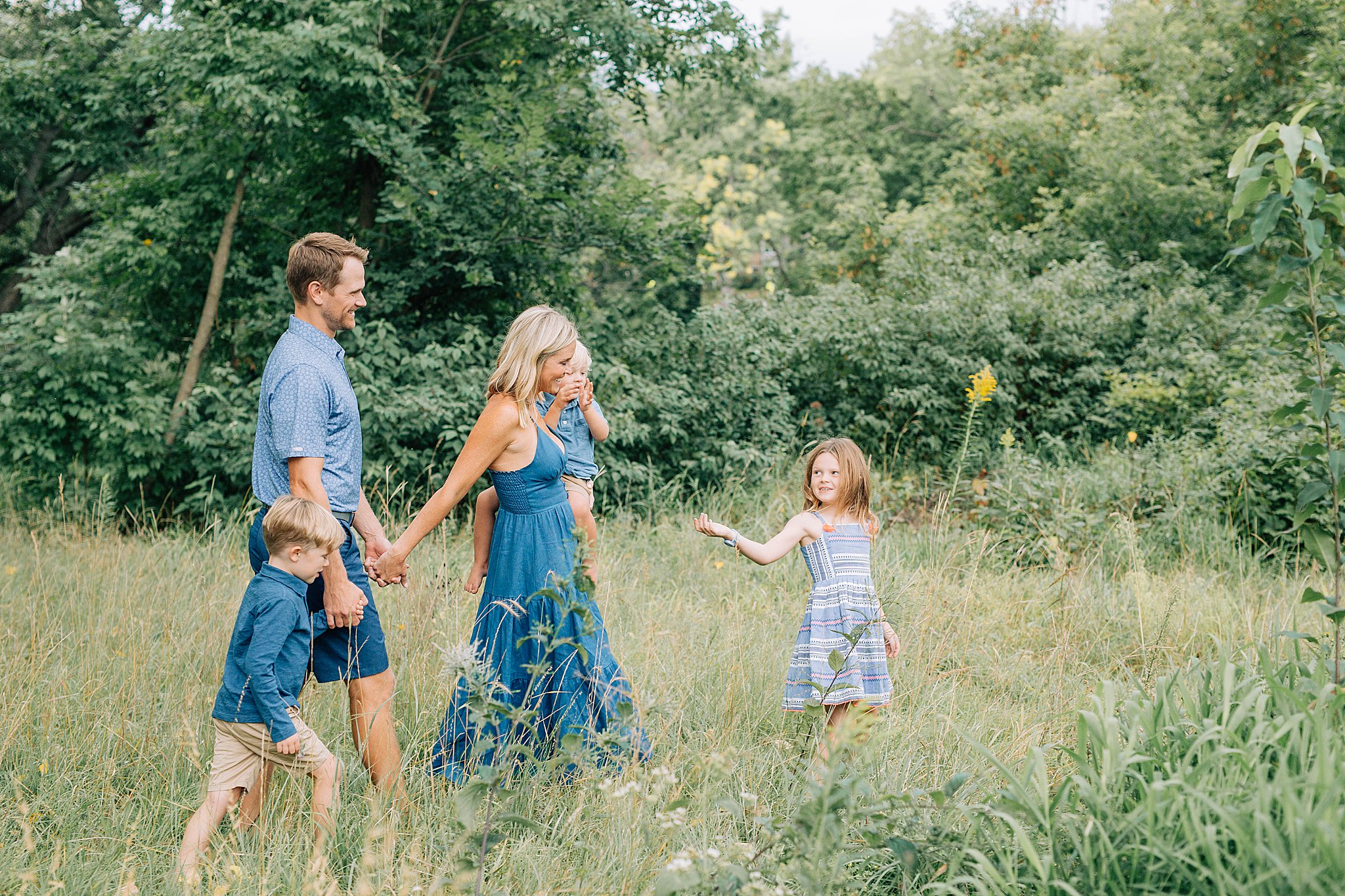 Family of five walking through meadow during their family pictures