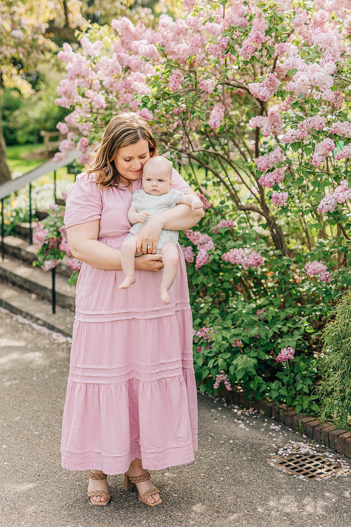 Spring pictures with momma and daughter in front of pink lilacs. 