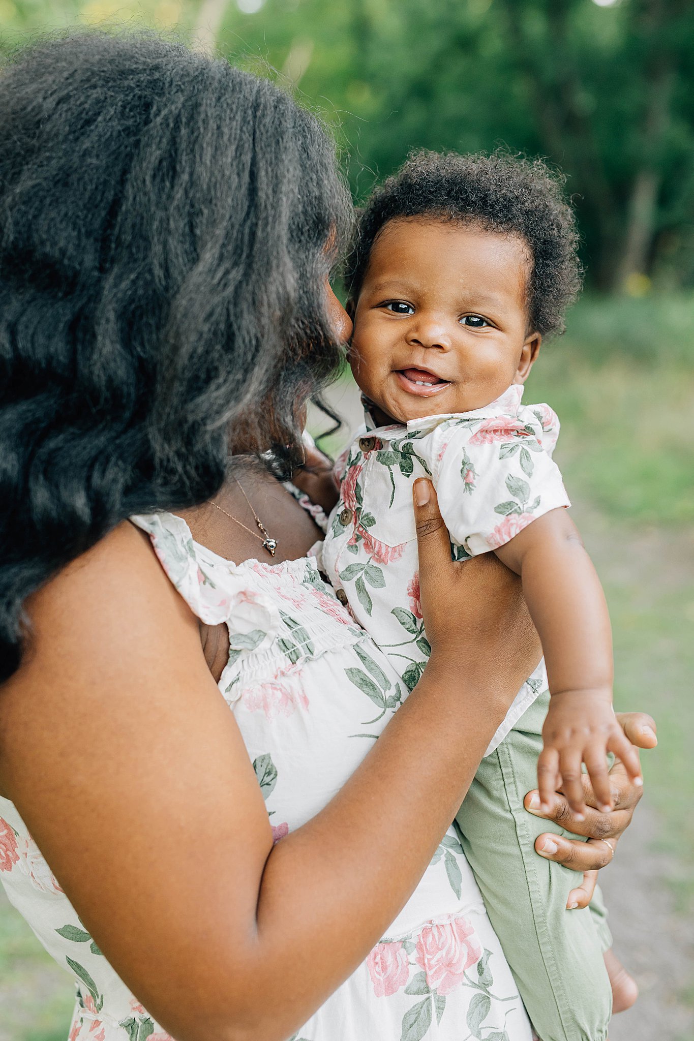 Mom holding smiling toddler during summer family pictures.