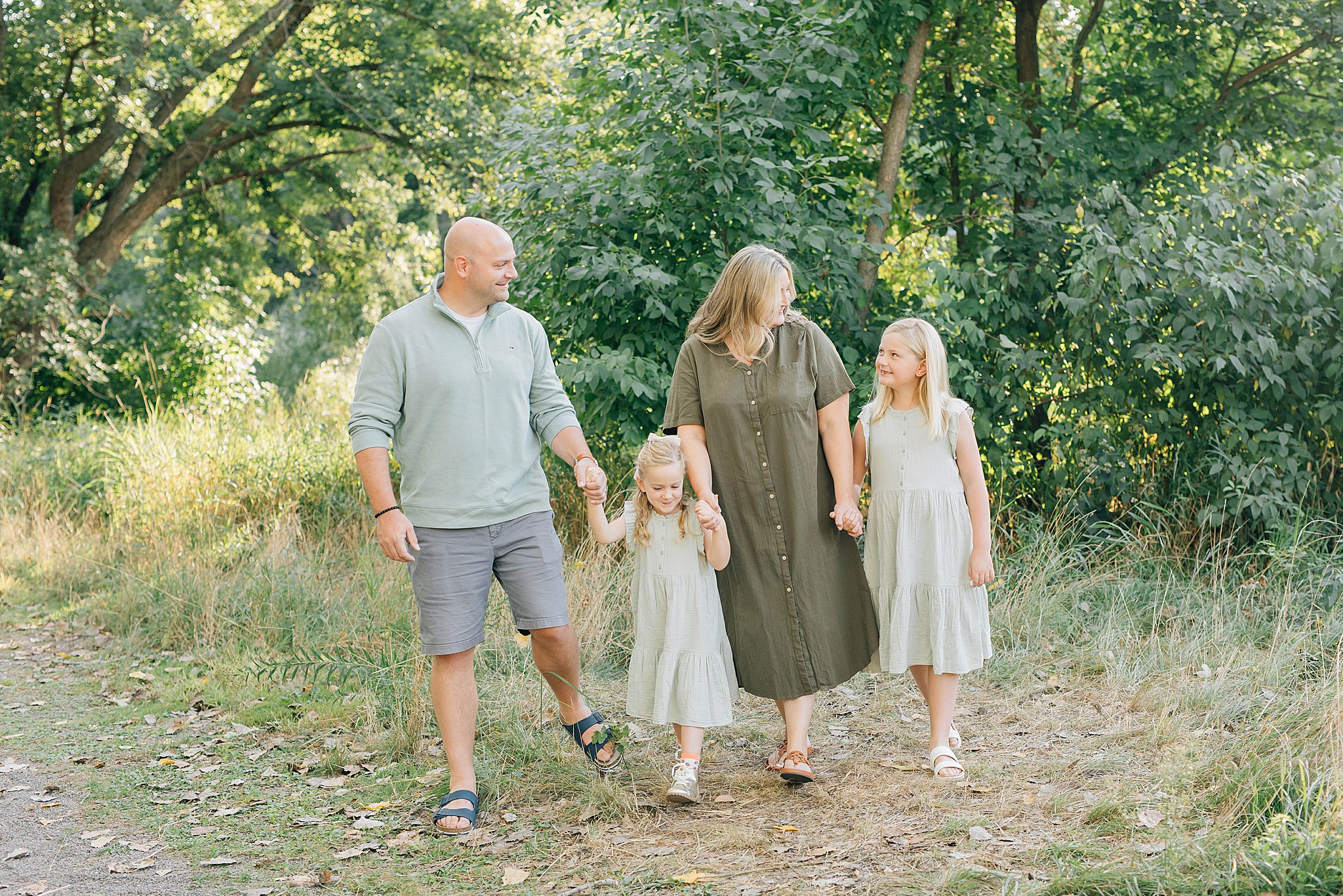 Dad, mom and two girls smiling and walking during Edina family photography.