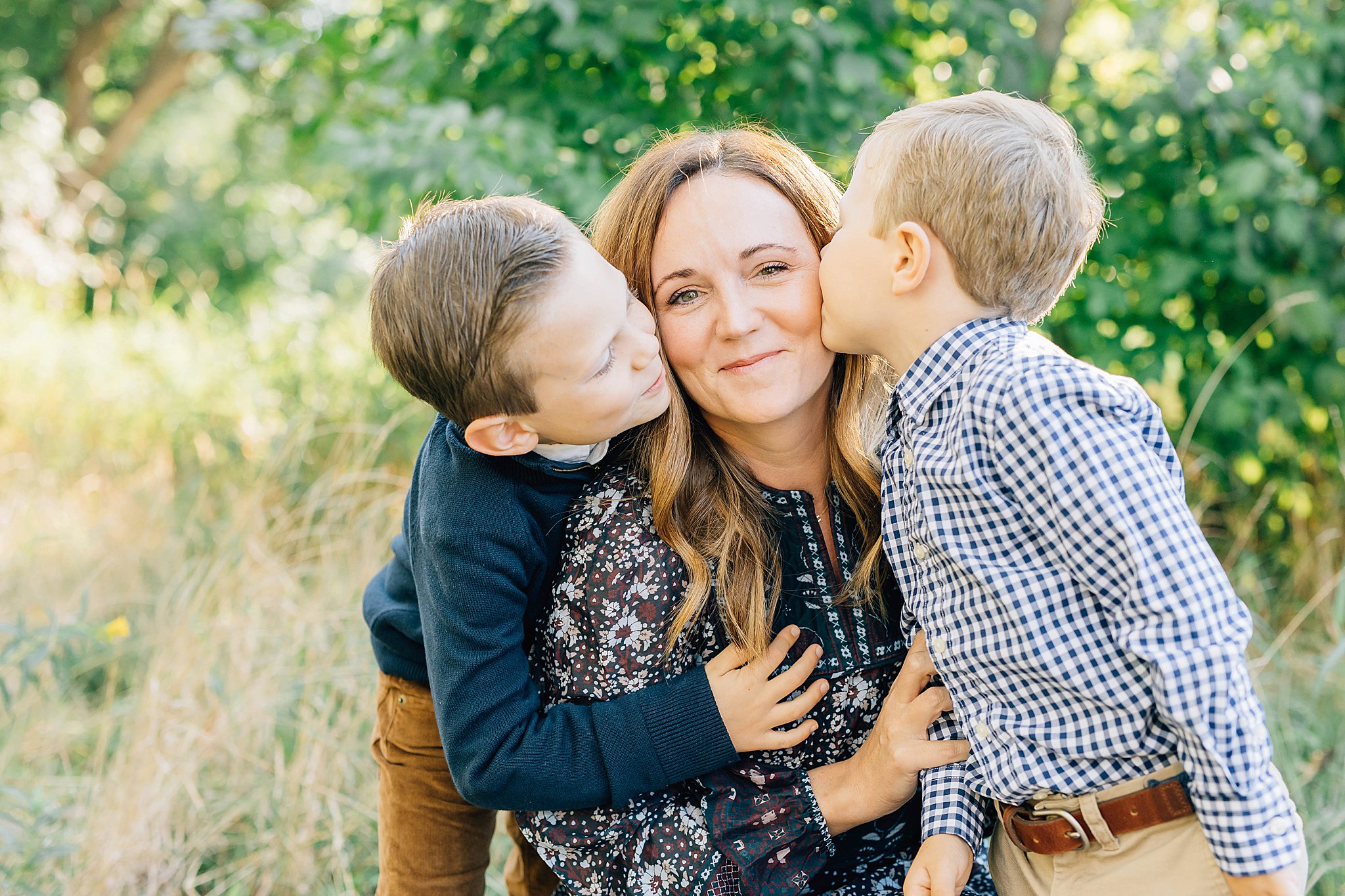 Two boys kissing mom's cheeks during family pictures with boys.