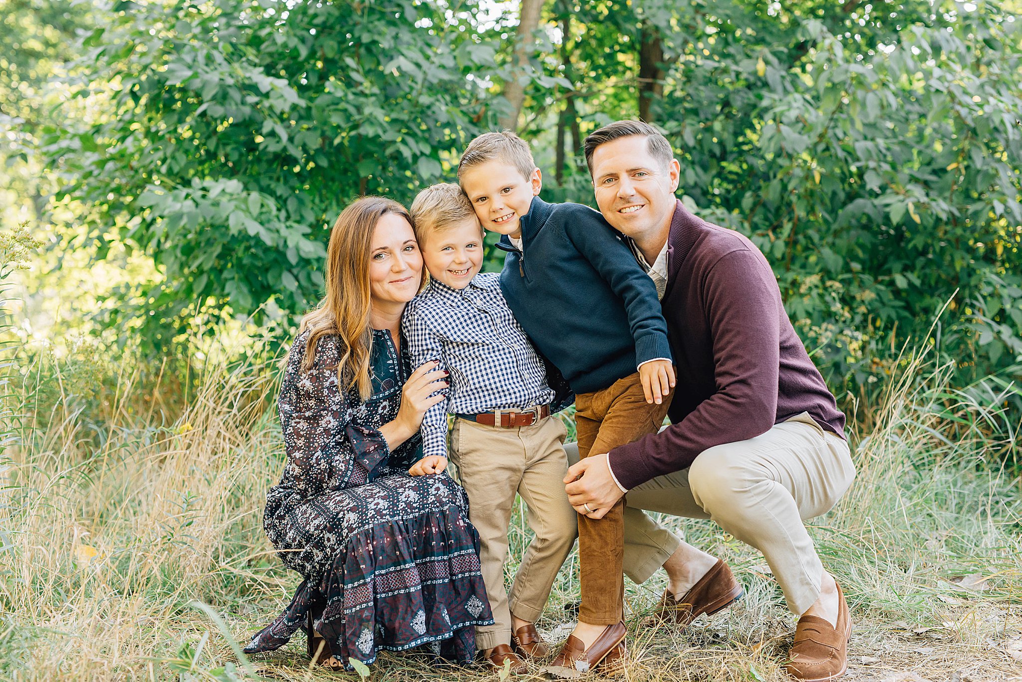 Two boys, mom and dad kneeling and smiling during family pictures with boys.