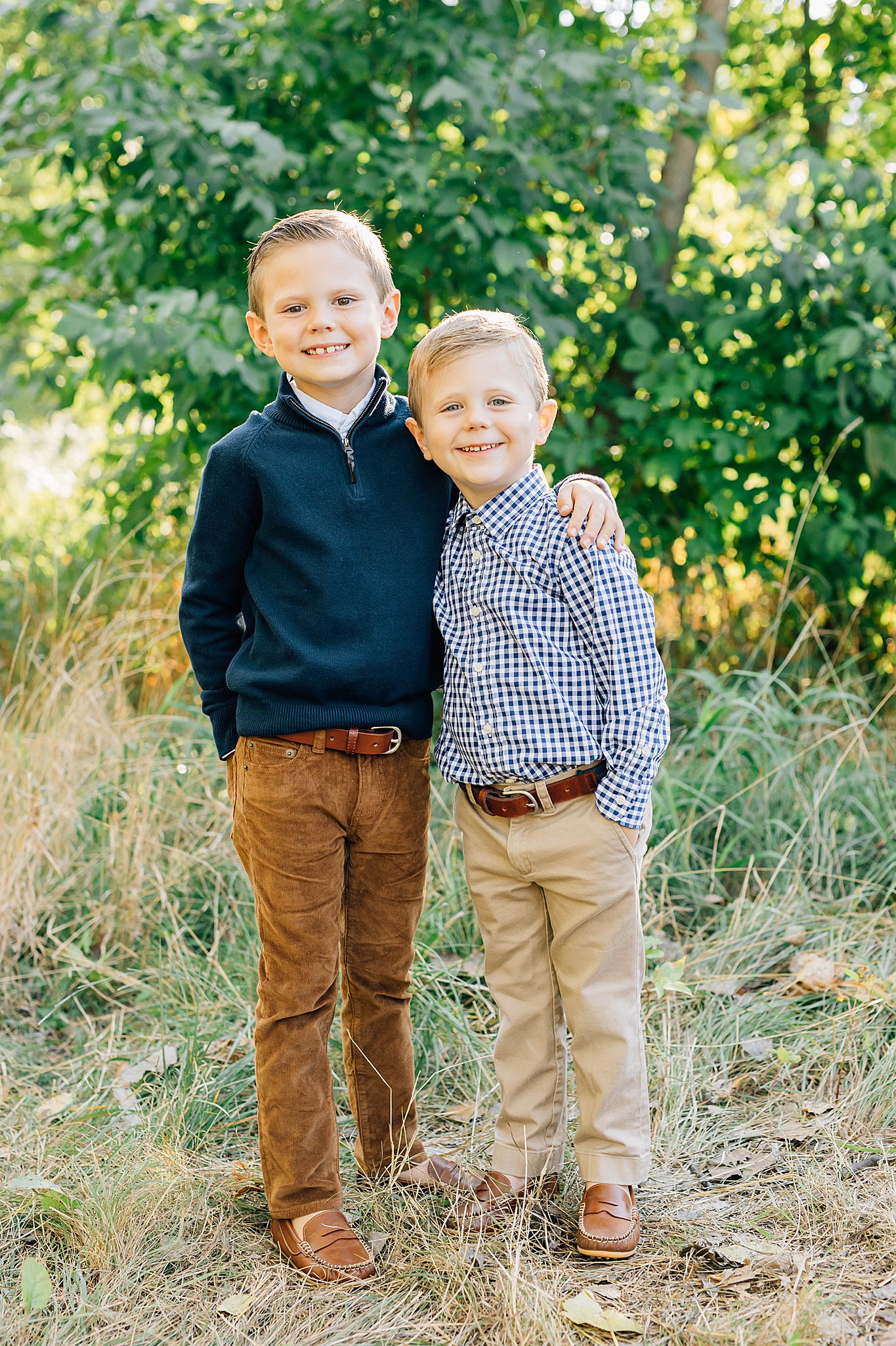 Two boys standing and smiling during family pictures with boys.
