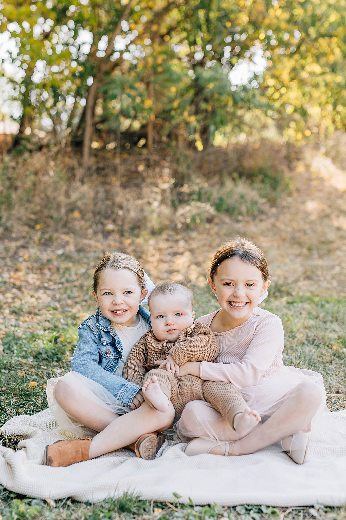 Three kids smiling during family pictures at Arneson Acres.