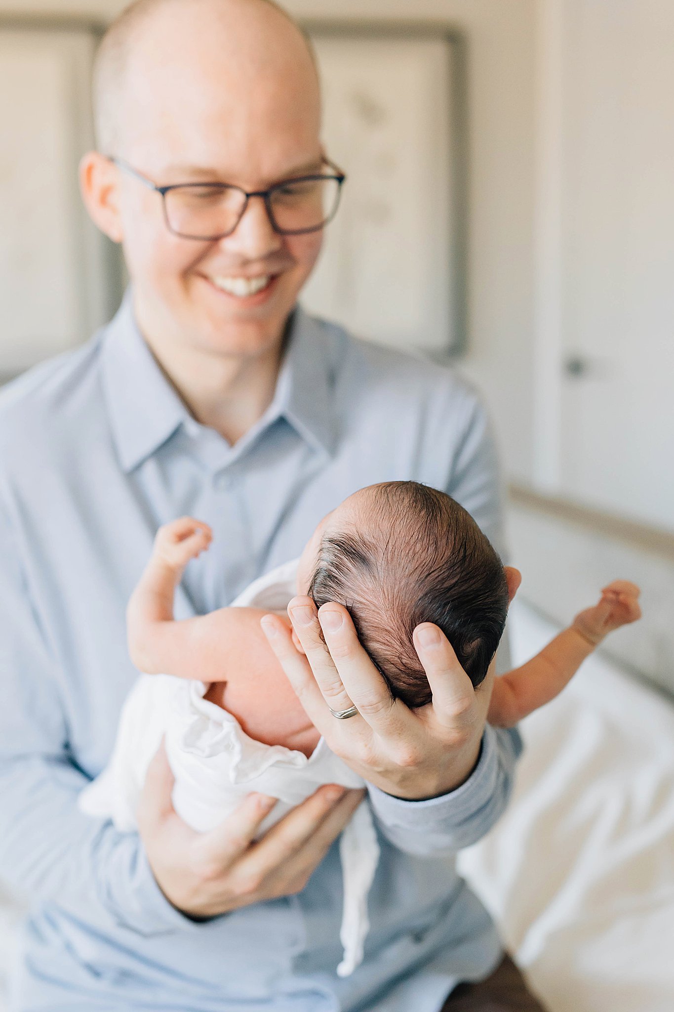 Dad holding newborn and smiling in Dad outfit ideas.
