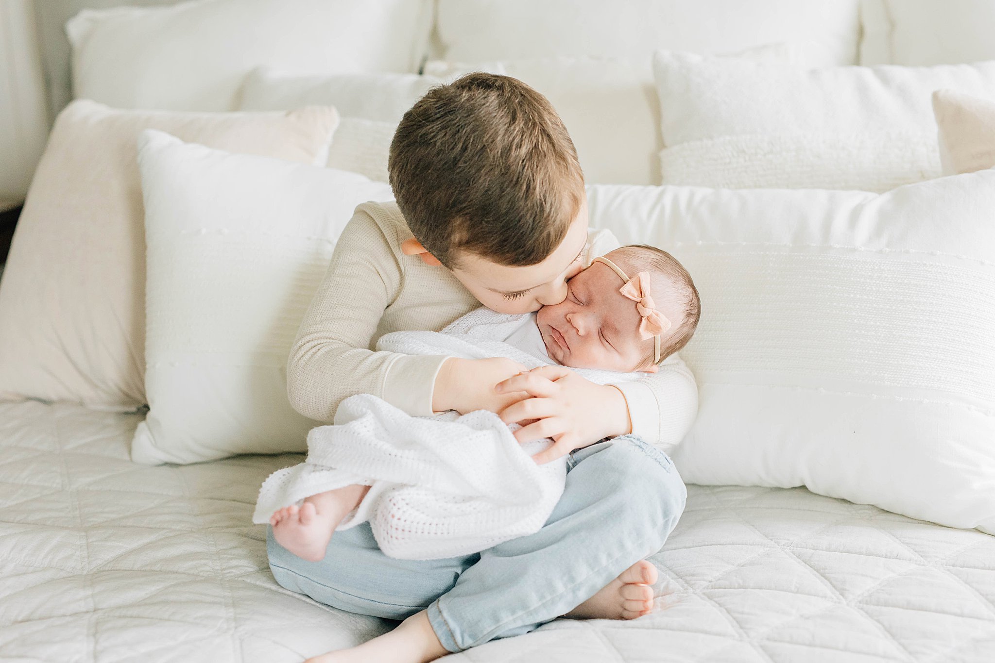 Brother kissing baby sister in what should my newborn wear blog post.