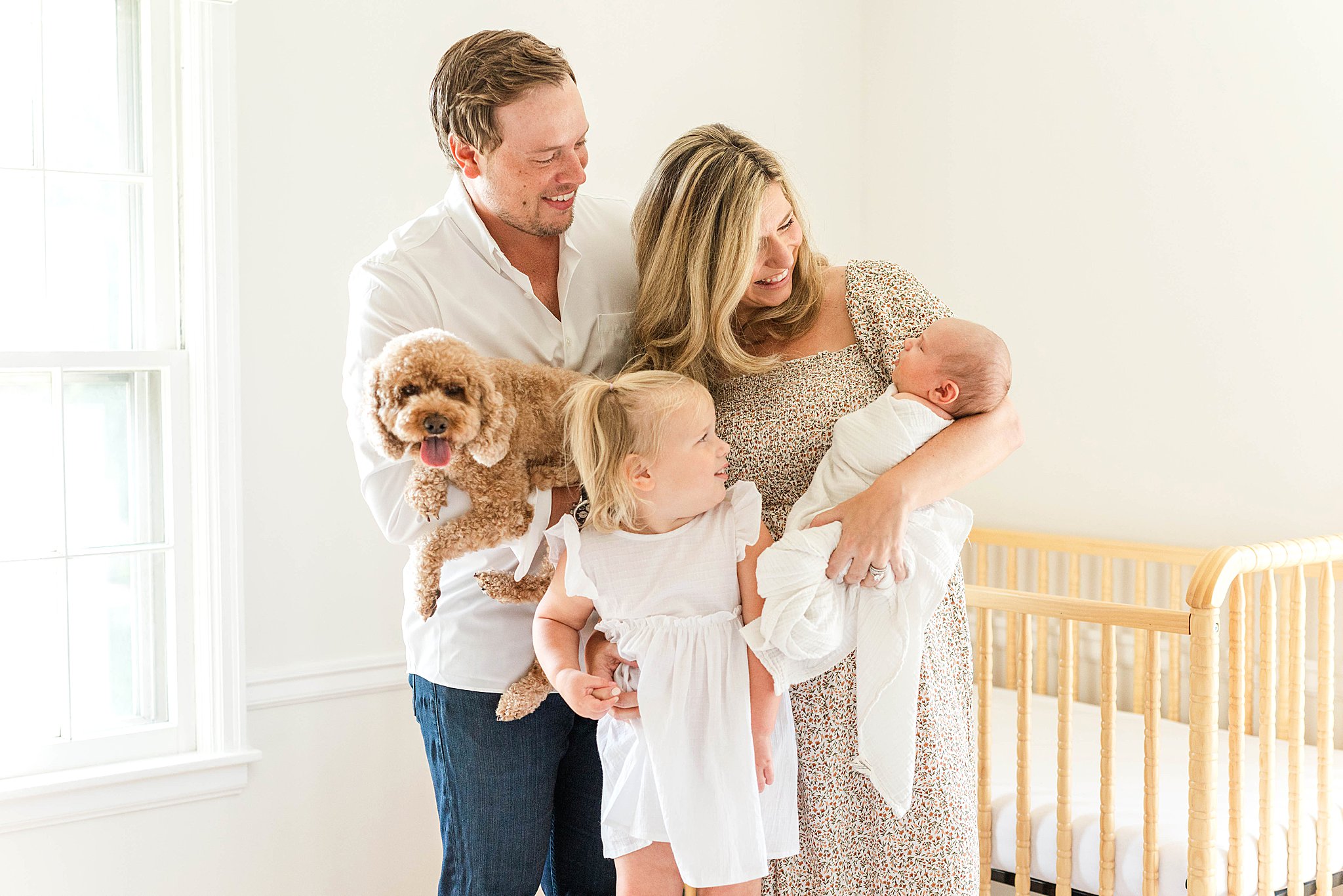 Mom holding baby and toddler, while dad holds dog during MN newborn photographer session.