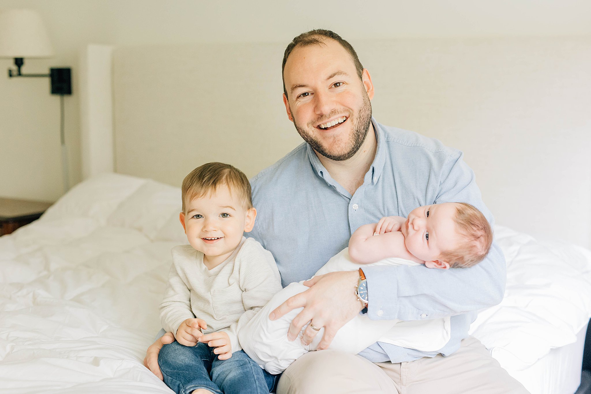 Dad holding baby and  older son during Bloomington In-home Newborn Pictures.
