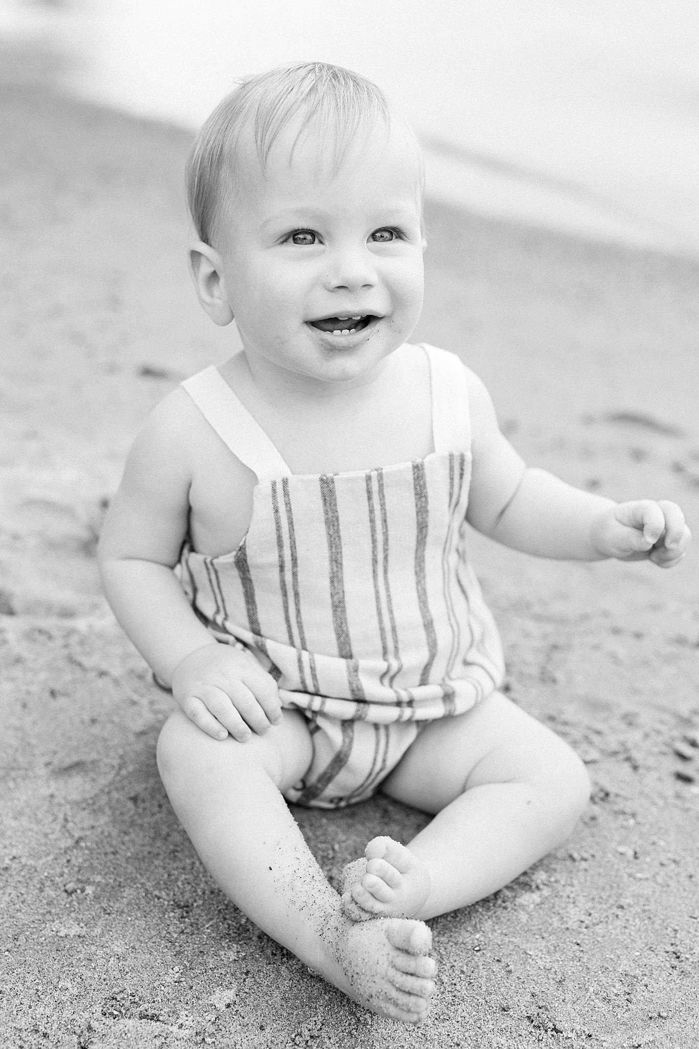 Boy sitting on beach and smiling during Lake Minnetonka Family Pictures.