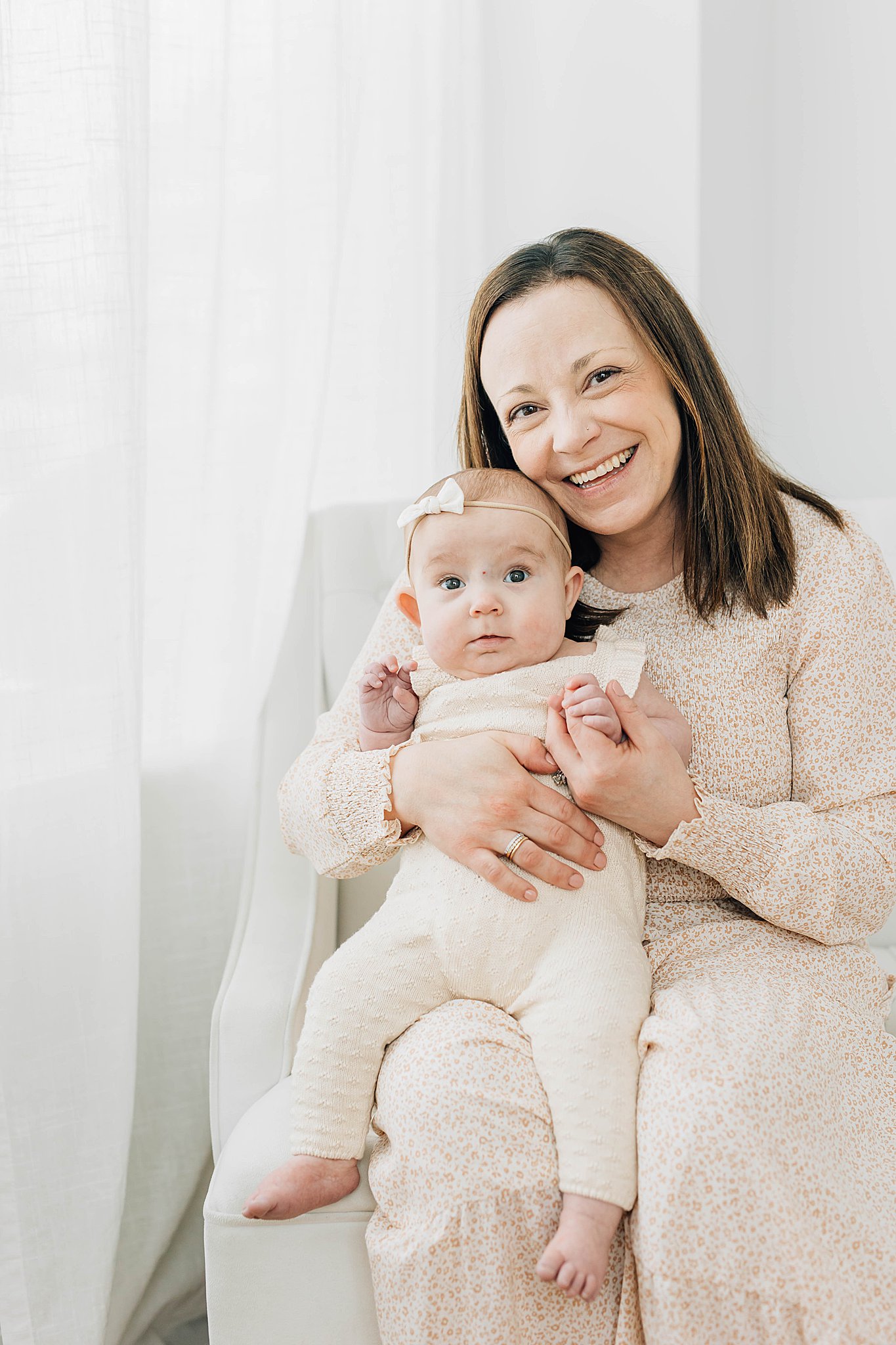 Mom smiling while holding baby during three Month Milestone Pictures.