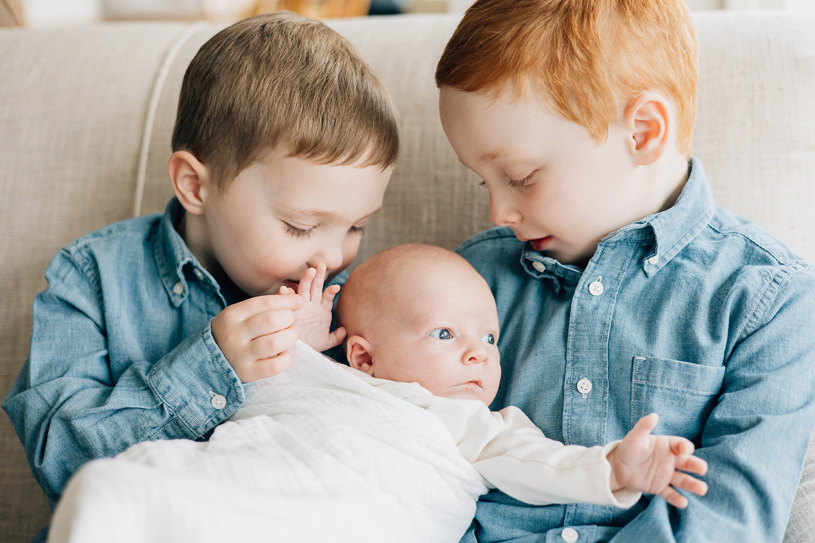 Siblings Holding Newborn Brother During Photoshoot
