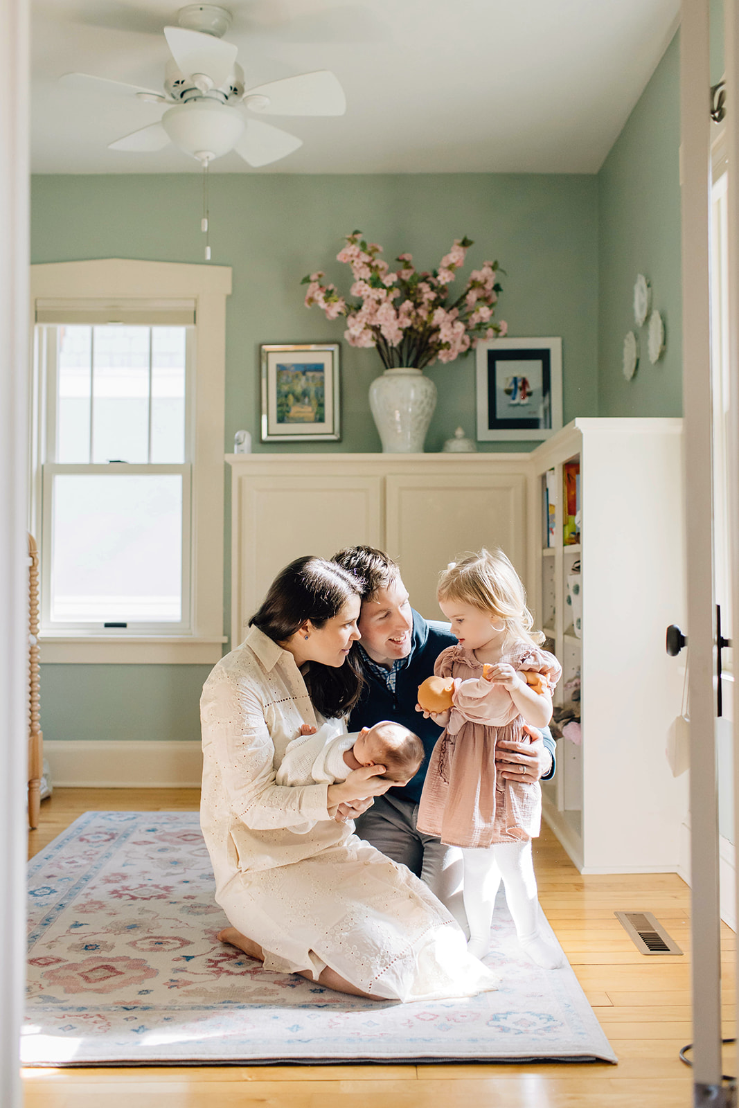 Mom Holds Newborn While Big Sister Looks at Her